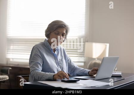 Agréable heureuse femme d'âge moyen comptable à la maison. Banque D'Images