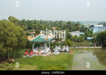 Temple, tombes et rizières dans le delta du Mékong depuis l'autoroute Trung Lương, Viet Nam Banque D'Images