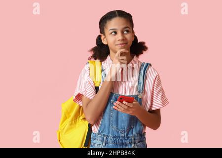 Étudiante afro-américaine avec téléphone sur fond rose Banque D'Images