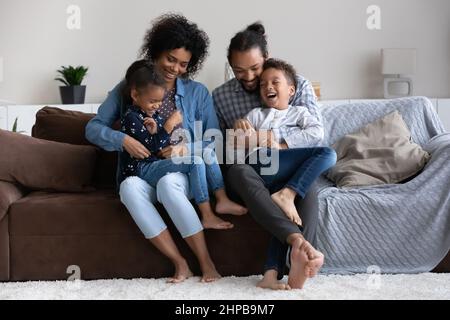 Heureux de s'occuper de jeunes parents afro-américains qui chatouillent les petits enfants. Banque D'Images