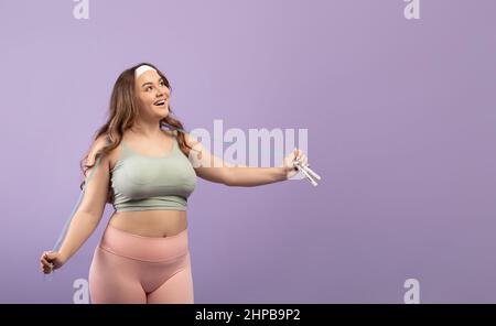 Surprise heureuse excitée plus grande taille de la jeune femme européenne dans les vêtements de sport avec la bouche ouverte et corde à sauter Banque D'Images