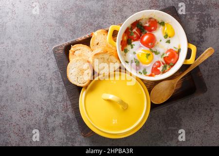 Œufs en Cocotte à la crème et au fromage servis avec des toasts chauds pour tremper les gros-plan dans le plateau en bois sur la table. Vue horizontale du dessus Banque D'Images