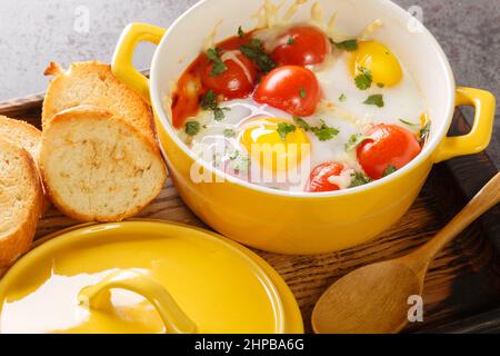 Œufs en Cocotte à la crème et au fromage servis avec des toasts chauds pour tremper les gros-plan dans le plateau en bois sur la table. Horizontale Banque D'Images