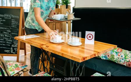 Une serveuse prend des tasses à la table Banque D'Images