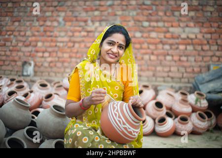 Portrait d'une femme indienne traditionnelle heureuse artiste potier peinture et décoration sur pot d'argile à vendre, artisanat, compétence inde. Banque D'Images