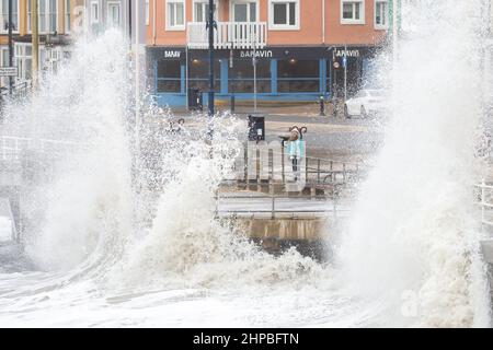 Aberystwyth, Ceredigion, pays de Galles, Royaume-Uni. 20th février 2022 Royaume-Uni Météo: Un enfant se tient à regarder les vagues le long de la promenade, tandis que le temps orageux se poursuit le long de la côte ouest d'Aberystwyth. Avec la combinaison de marée haute, apportant les mers rugueuses s'écrasant contre la promenade et les défenses de mer. © Ian Jones/Alamy Live News Banque D'Images