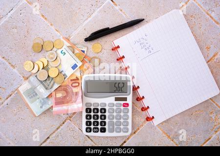 billet de banque et pièces de monnaie en euros posés sur une table avec une calculatrice et un bloc-notes Banque D'Images