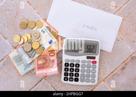 billet de banque et pièces de monnaie en euros posés sur une table avec une calculatrice et une enveloppe Banque D'Images