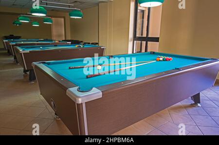 Une rangée de tables de billard avec des boules et des éléments dans la salle de sports du club de loisirs Banque D'Images