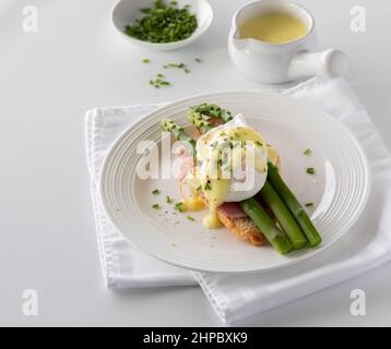 Une assiette d'œufs benedict surmontée de sauce hollandaise et de ciboulette. Banque D'Images