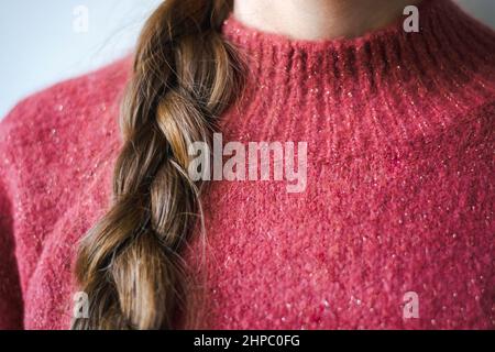 Femme en gros plan avec tresse portant un pull d'hiver rose chaud et doux à paillettes Banque D'Images