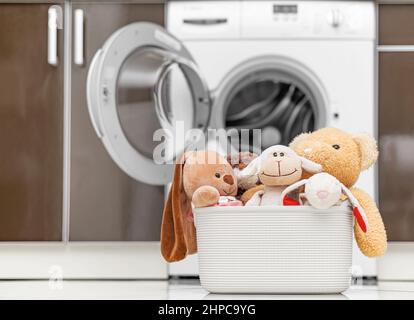 Jouets pour enfants dans un panier à l'arrière-plan d'une machine à laver. Banque D'Images