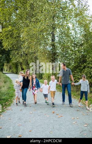 Famille de huit personnes, tenir les mains marcher sur l'oathway dans le parc naturel. Banque D'Images