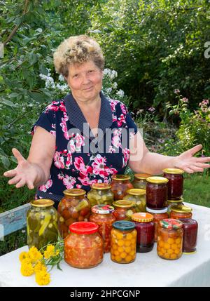 Femme gaie avec des légumes en conserve faits maison dans le jardin Banque D'Images