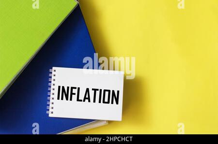Le mot inflation est écrit sur un bloc-notes et un fond jaune avec des dossiers de documents. Banque D'Images
