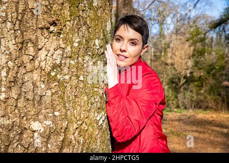La jeune femme embrasse un grand chêne. La femme touche le tronc et ressent l'énergie de la nature. Concept de bien-être et d'amour pour natu Banque D'Images