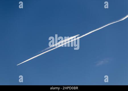 Contrailles - deux avions qui volent dans des directions opposées avec des sentiers de condensation blanche dans le ciel bleu Banque D'Images