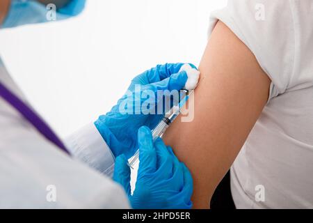 Le médecin tient une seringue avant de donner une injection à un patient dans un masque médical. Vaccin Covid-19 ou coronavirus. Banque D'Images