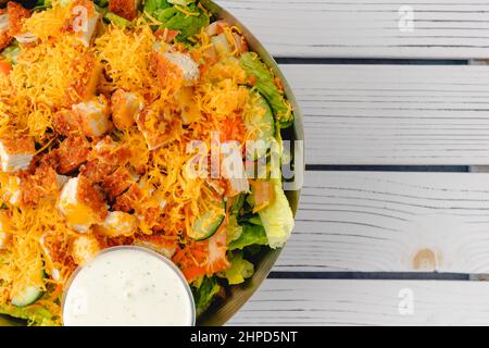 Salade de poulet avec garniture de cheddar râpé et sauce ranch dans un bol sur fond de bois, espace de copie Banque D'Images