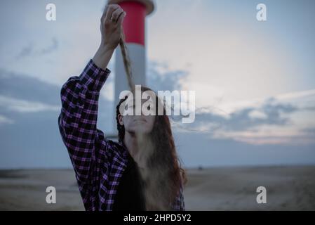 Femme tombant une poignée de sable devant son visage. Temps et perdu Banque D'Images