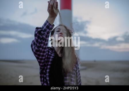 Femme tombant une poignée de sable devant son visage. Temps et perdu Banque D'Images