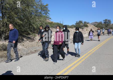 Les 24 relais coureurs et les membres de la San Carlos Apache Tribe marche la finale ? Mille de la course de 13 miles transportant le bâton avec les plumes sacrées jusqu'au terrain de camping Oak Flat à Miami, Arizona, États-Unis, le 19 février 2022. Inscrite au Registre national des lieux historiques, cette parcelle de terre connue sous le nom de Oak Flat a été considérée comme un lieu sacré par l'Apache pendant des milliers d'années où ils vont là pour prier, tenir des cérémonies, et considéré comme la maison des êtres spirituels. Depuis que l'un des plus grands gisements de cuivre au monde a été découvert à 7 000 pieds au-dessous de Oak Flat, une bataille a fait rage p Banque D'Images