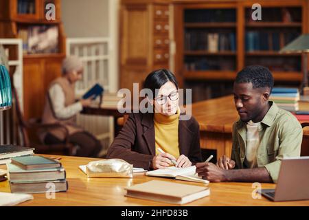Portrait d'une femme professeur tutorat étudiant noir à l'intérieur d'une bibliothèque classique à l'université Banque D'Images