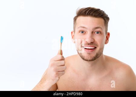 Le sourire d'un jeune homme en gros plan. Un homme tient une brosse à dents dans la main. Le concept de soins buccaux. Banque D'Images