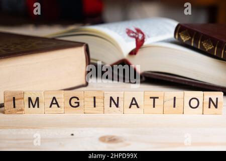 MOT IMAGINATION écrit avec des blocs de bois, à côté de livres sur une table. Banque D'Images