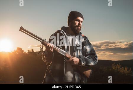 Fusil Hunter silhoueté dans beau coucher de soleil. Chasseur pendant la saison de chasse de l'automne. La chasse est la pratique de tuer ou de piéger des animaux. Banque D'Images