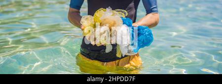 L'homme collecte des paquets de la belle mer turquoise. Pollution de plage paradisiaque. Problème de déversés déchets de déchets de déchets de déchets sur le sable de plage causé par Banque D'Images