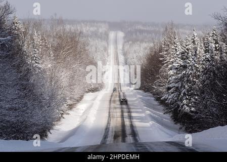 Route uebec 216, dans la région de Chaudière-Appalaches, en hiver avec une grande vue panoramique sur la forêt neigeuse bordant la route neigeuse partielle. Banque D'Images