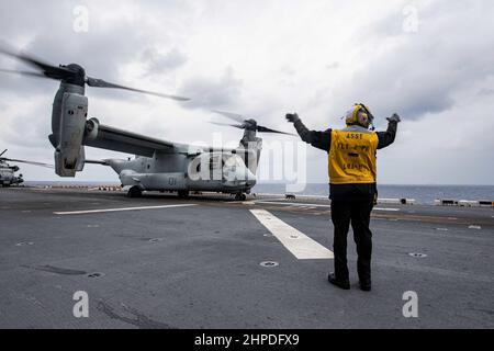 MER DES PHILIPPINES (fév 17, 2022) Aviation Boatswain’s Mate (Handling) 2nd classe Robert Wynn, d’Apopka, en Floride, affecté au navire d’assaut amphibie déployé vers l’avant USS America (LHA 6), résigne un avion de transport à plateau MV-22B Osprey de l’unité expéditionnaire maritime (UMM) de 31st pour le décollage sur le pont de vol du navire. L'Amérique, navire chef de file du America Amphiobie Ready Group, ainsi que le MEU 31st, opère dans la zone de responsabilité de la flotte américaine 7th afin d'améliorer l'interopérabilité avec les alliés et les partenaires et de servir de force de réaction prête à l'emploi pour défendre la paix et la stabilité dans le RE Indo-Pacifique Banque D'Images