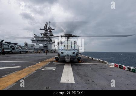 MER DES PHILIPPINES (fév 17, 2022) un hélicoptère MH-60s Sea Hawk de l'Escadron de combat de la mer (HSC) 25 se prépare à prendre le pont de vol du navire d'assaut amphibie déployé vers l'avant USS America (LHA 6). L'Amérique, navire chef de file du America Amphiobie Ready Group, ainsi que l'unité expéditionnaire maritime 31st, opère dans la zone de responsabilité de la flotte américaine 7th afin d'améliorer l'interopérabilité avec les alliés et les partenaires et de servir de force de réaction prête à l'emploi pour défendre la paix et la stabilité dans la région Indo-Pacifique. (É.-U. Photo de la marine par le Spécialiste des communications de masse 3rd classe Thomas B. Conta Banque D'Images