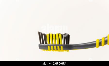 Hygiène bucco-dentaire. Brosse à dents noire et jaune sur fond blanc. Banque D'Images