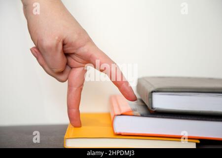 Soif de connaissances. Escaliers des livres. Main symbolise qu'un homme monte l'échelle de la connaissance sur un fond blanc Banque D'Images