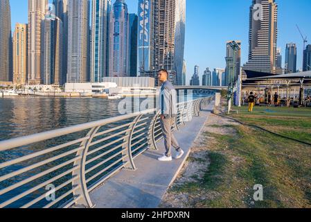 Jeune homme marchant sur la promenade de Dubai Marina. Banque D'Images