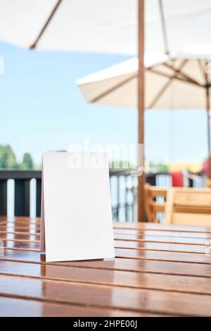 Affiche vierge sur une table sur la terrasse d'un restaurant, à l'extérieur, en été. Espace blanc pour afficher un texte, un menu, des produits, des promotions ou d'autres informations Banque D'Images