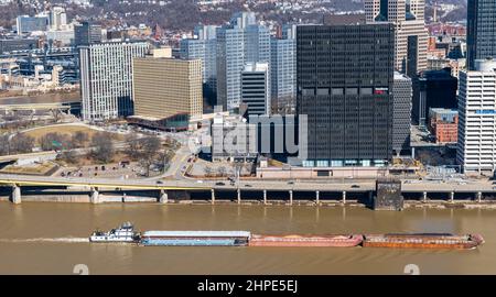 Un remorqueur poussant quatre barges sur une rivière Monongahela boueuse à côté du centre-ville de Pittsburgh, Pennsylvanie, États-Unis Banque D'Images