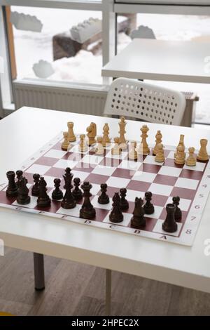 Les figures du jeu de plateau d'échecs sur la table au-dessus de la fenêtre floue à l'école en classe blanche. Personne Banque D'Images