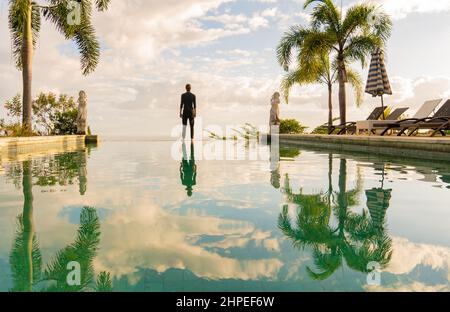 Un homme debout au bord de la piscine à débordement Banque D'Images