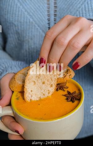 Femme tenant une soupe épicée à la carotte et au gingembre maison. Soupe traditionnelle de citrouille de saison à la texture soyeuse crémeuse. Saine alimentation végétalienne propre. Banque D'Images