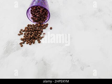 Grains de café renversés par une tasse bleue sur fond Banque D'Images