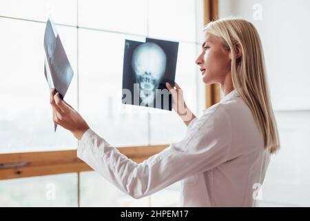 La radiologiste féminine examine les acquisitions du crâne Banque D'Images
