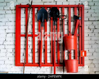 Fixé sur un mur Bouclier de feu avec des outils de lutte contre l'incendie. Pelle, crochet , ax, godet conique, extincteur et d'autres équipements pendu le point d'incendie. Banque D'Images