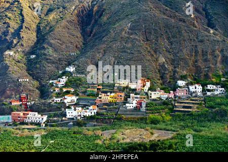 Village d'Hermigua, la Gomera, îles Canaries: Maisons colorées sur une pente de montagne et bananier dans la vallée, en hiver. Banque D'Images