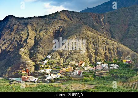 Village d'Hermigua, la Gomera, îles Canaries: Maisons colorées sur une pente de montagne et bananier dans la vallée, en hiver. Banque D'Images