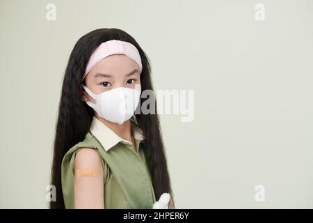 Portrait d'une petite fille asiatique dans un masque protecteur regardant l'appareil photo contre le fond blanc Banque D'Images