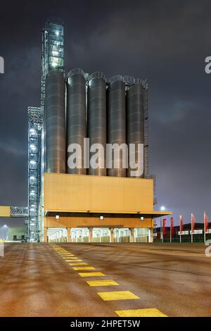 Scène nocturne avec une usine pétrochimique avec de grands silos et des marquages routiers au premier plan, Port d'Anvers Banque D'Images