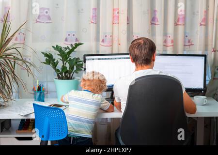 Père avec enfant essayant de travailler de la maison pendant la quarantaine. Restez à la maison, travaillez à partir du concept de maison pendant la pandémie de coronavirus Banque D'Images